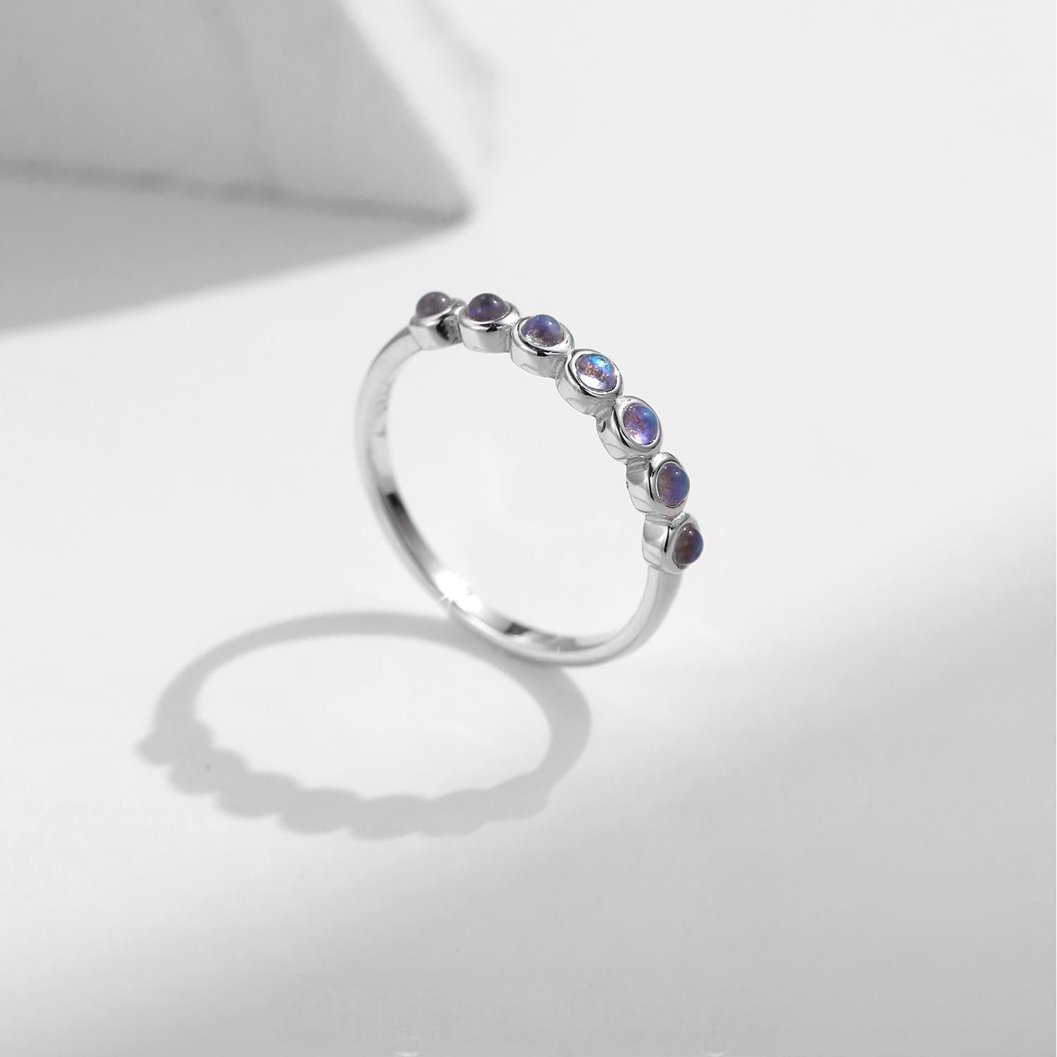 Stackable sterling silver moonstone ring on finger, Ins style moonstone ring with celestial glow, Recycled silver moonstone stacking band jewelry,Close-up of natural moonstone in silver ring setting, Minimalist moonstone ring for layered arm candy