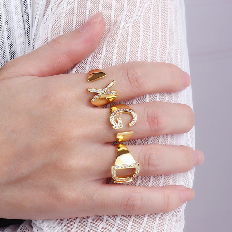 Adjustable brass letter A ring with micro-paved zirconia stones close-up, Top view of 18K gold-plated brass alphabet ring set spread on velvet, Side view of brass letter D ring worn on finger with adjustable opening, Macro shot of zirconia stone details and brass texture on alphabet ring, 