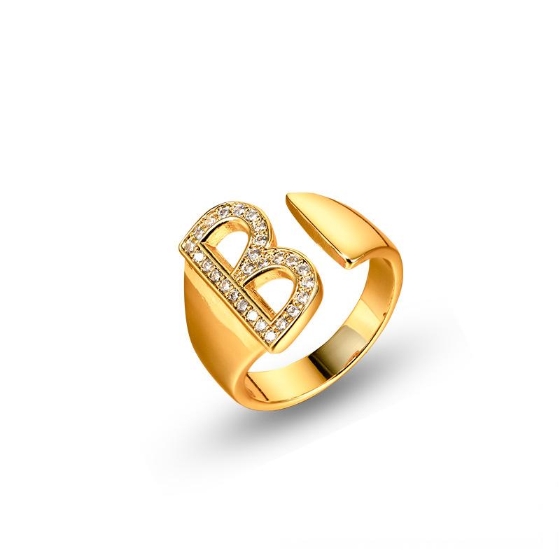 Adjustable brass letter A ring with micro-paved zirconia stones close-up, Top view of 18K gold-plated brass alphabet ring set spread on velvet, Side view of brass letter D ring worn on finger with adjustable opening, Macro shot of zirconia stone details and brass texture on alphabet ring, 