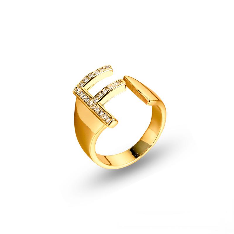 Adjustable brass letter A ring with micro-paved zirconia stones close-up, Top view of 18K gold-plated brass alphabet ring set spread on velvet, Side view of brass letter D ring worn on finger with adjustable opening, Macro shot of zirconia stone details and brass texture on alphabet ring, 